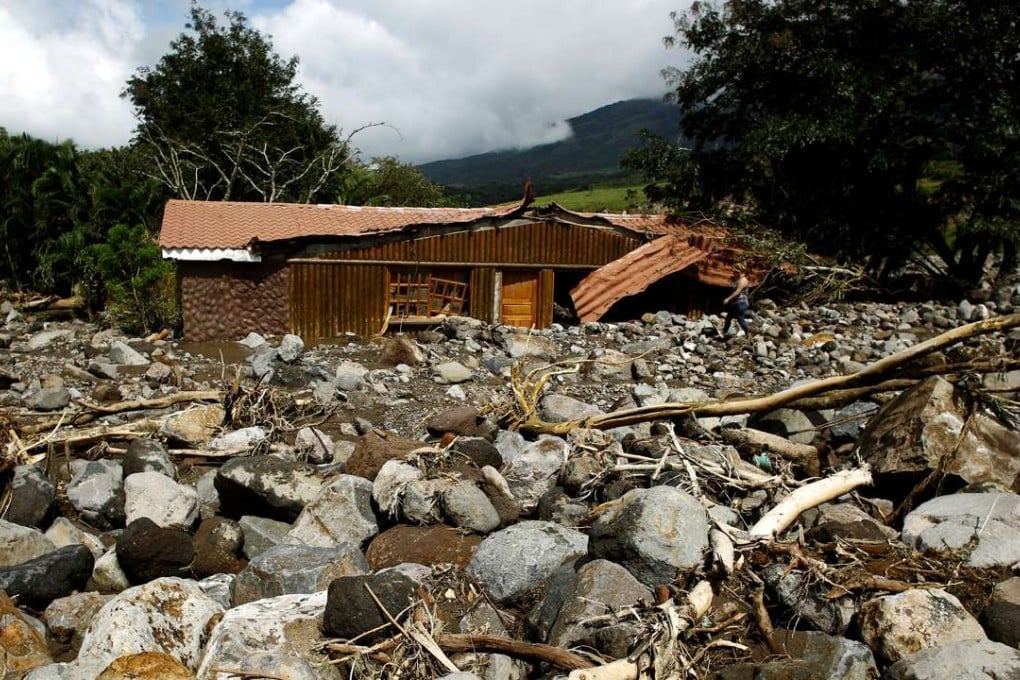 A woman walks in front of houses destroyed by a landslide after Hurricane Otto hit in Guayabo de Bagaces, Costa Rica. Photo: Reuters