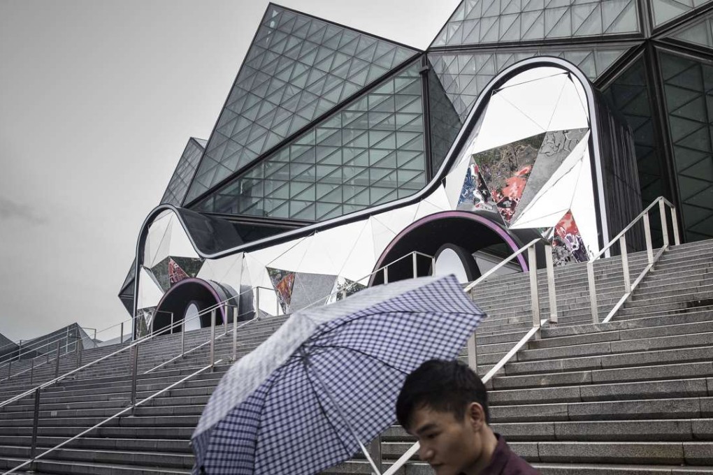 L’Occitane International said its profit grew in the half year through September 30 thanks to rising sales in emerging markets which offset a slump in Europe and Hong Kong. Depicted is a man walking past the entrance to the Shenzhen Universiade Sports Center, shaped in the form of the Tmall Cat, mascot for Alibaba’s Tmall online marketplace. Photo: Bloomberg