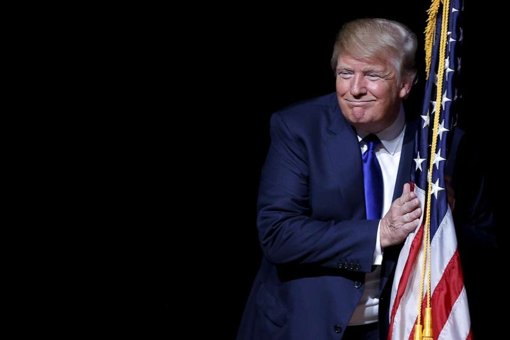 Donald Trump hugs a US flag on the campaign trail in New Hampshire earlier this year. Photo: Reuters