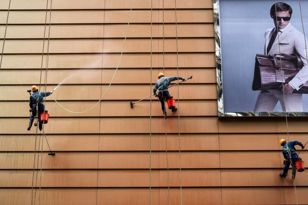 Workers clean the exterior of a building next to an advertisement in Wuxi, Jiangsu province. Photo: Reuters