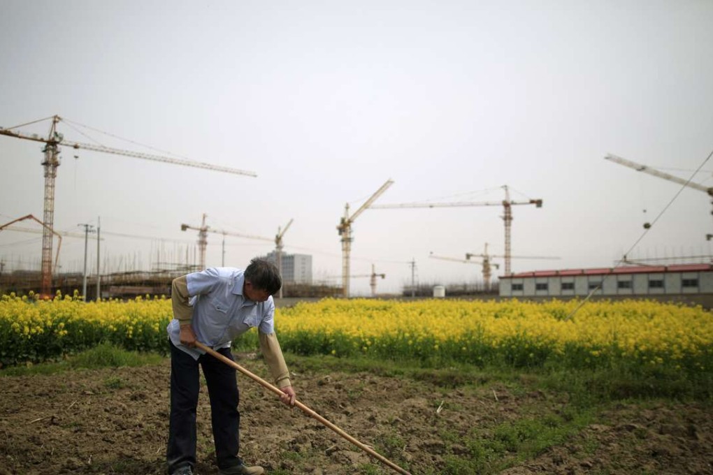A farmer tends to a field in front of a construction site in Shanghai. The push for unemployed people to consider a life in the countryside comes at a time when the nation is struggling to create jobs in the cities. Photo: Reuters