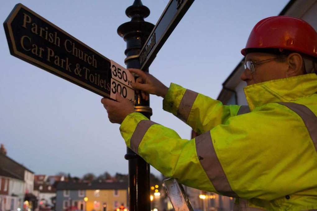 Tony Bennett, secretary of the organisation Active Resistance to Metrication (ARM), changes a signpost marking from metric to imperial measurement. Photo: AFP