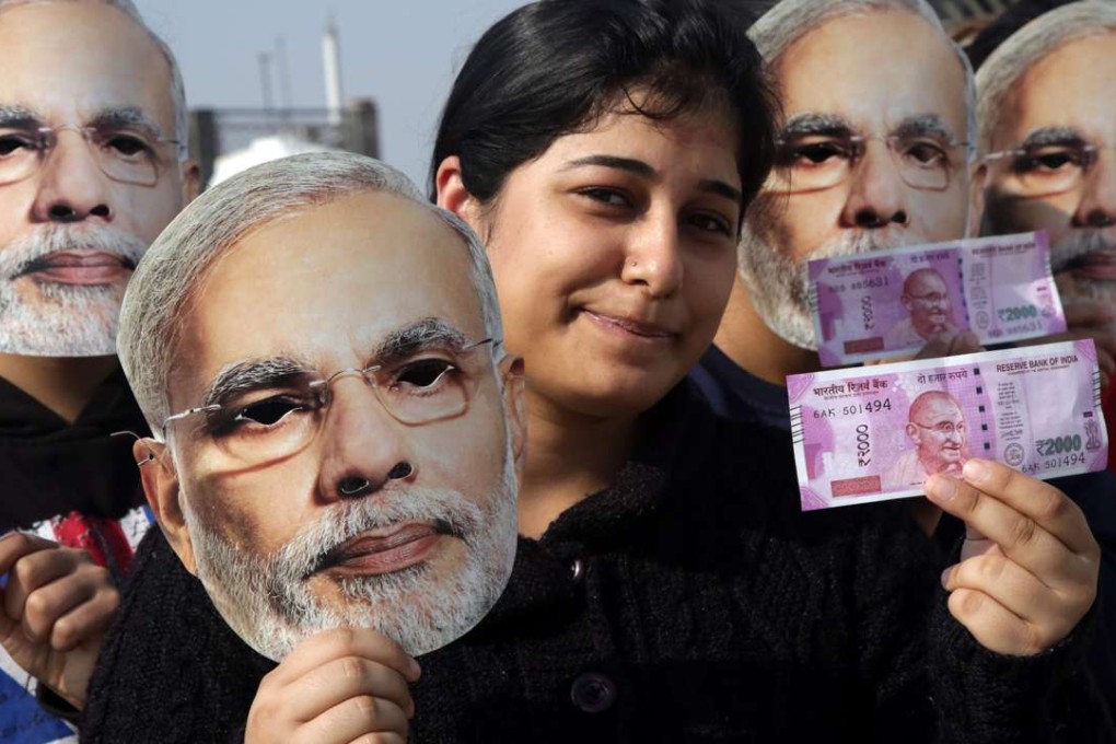 Indian girls in Jammu wear masks depicting Narendra Modi and hold up new currency notes in support of the prime minister’s demonetisation drive to stamp out the use of black money. Photo: EPA