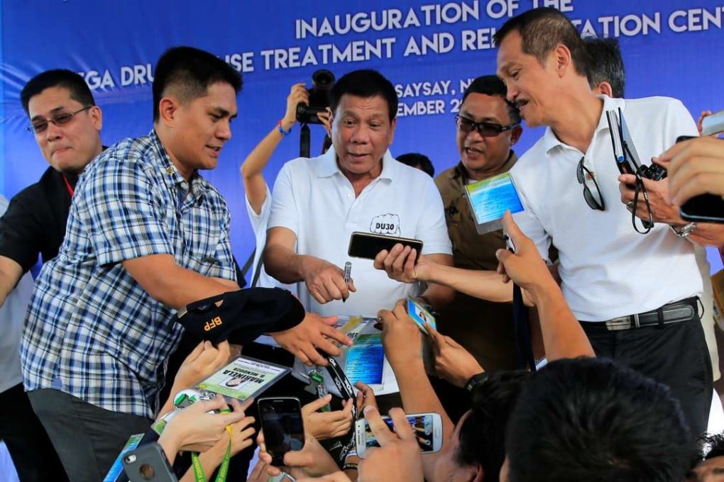 Philippine President Rodrigo Duterte (C) gestures while government workers takes pictures of him after the inauguration of a drug abuse treatment and rehabilitation centre. Photo: Reuters