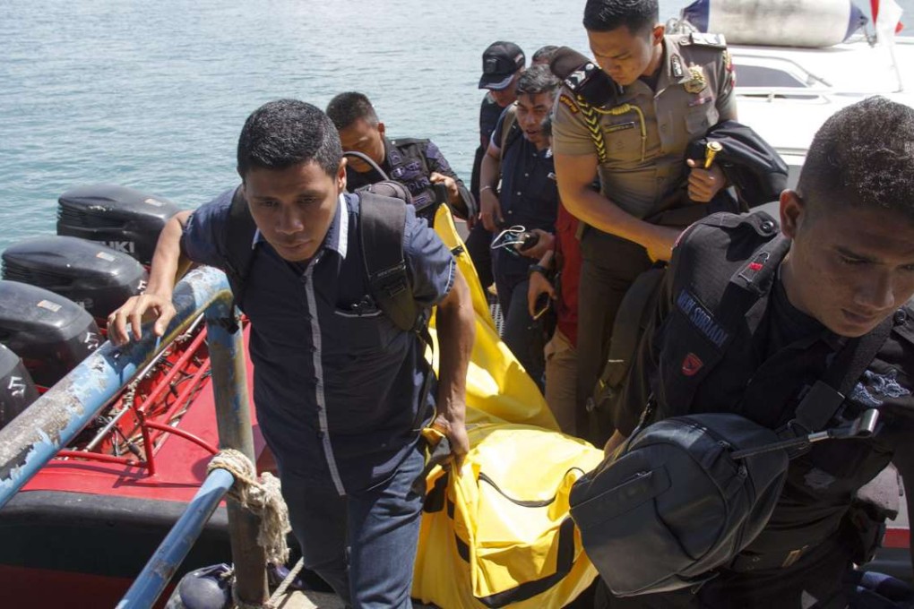 Indonesian police officers carry the body of a victim after a police plane crash in Senayang waters. Photo: EPA