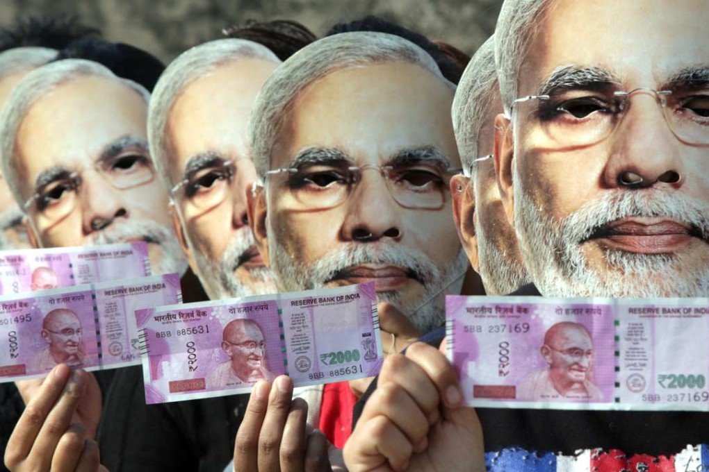 Indian girls in Jammu wear masks depicting Narendra Modi and hold up new currency notes in support of the prime minister’s demonetisation drive to stamp out the use of black money. Photo: EPA