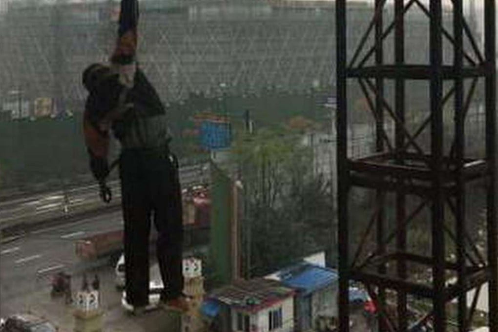 The construction worker hangs suspended from a safety rope 20 metres off the ground after falling from a crane in Zhejiang province on Sunday. Photo: SCMP Pictures