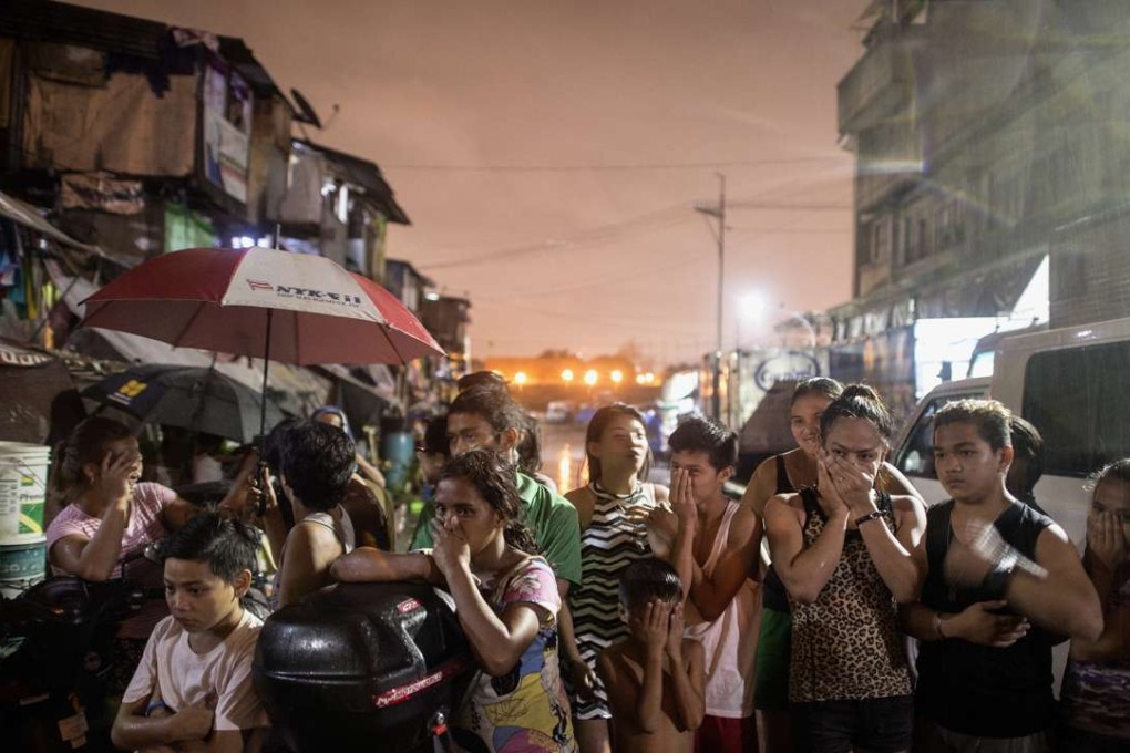 Residents near a crime scene where three alleged drug dealers were killed after a drug raid in a shanty community in Manila. Photo: AFP