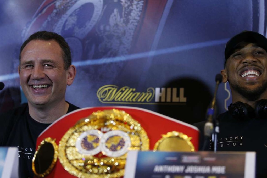 Anthony Joshua enjoys a joke with coach Robert McCracken ahead of his heavyweight world title bout on Saturday. Photo: Reuters