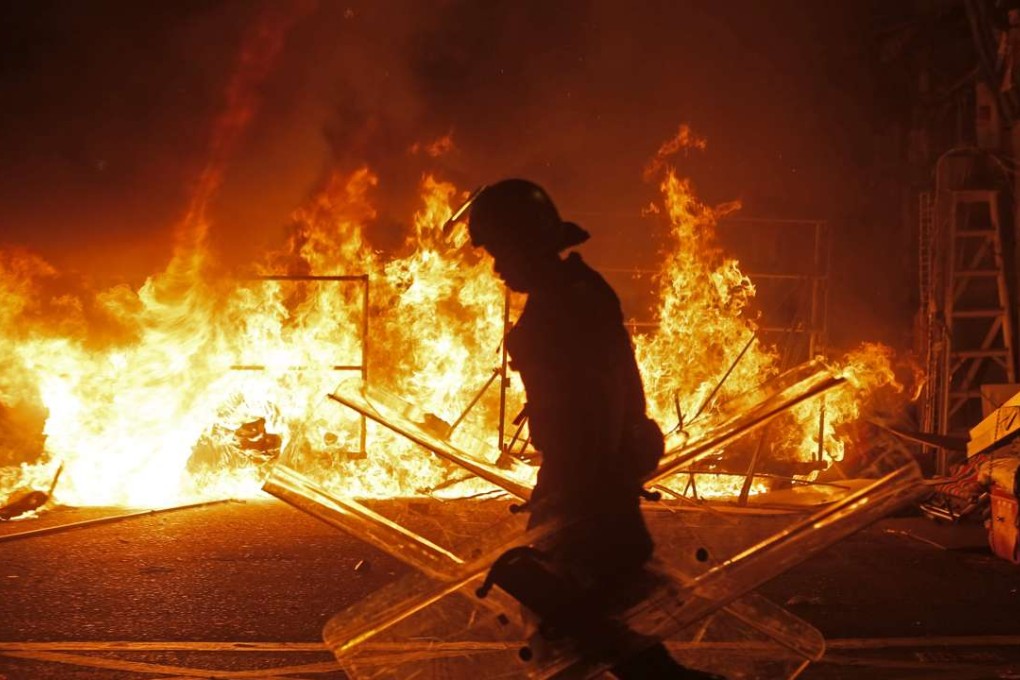 A police officer walks past a fire set by rioters in Mong Kok, Hong Kong, in February 2016. Photo: AP
