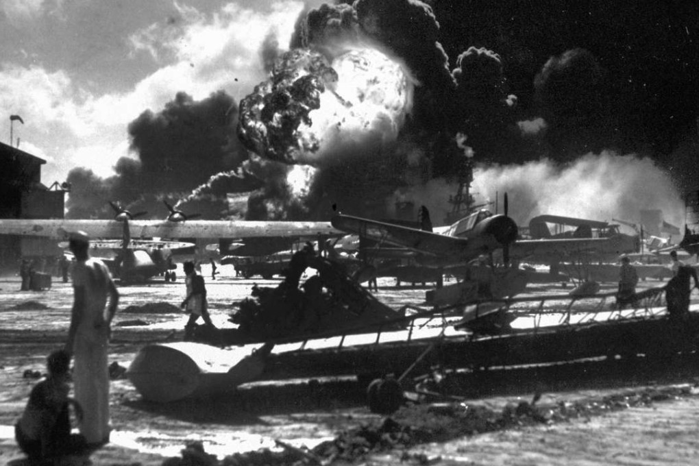 Sailors stand among wrecked airplanes at Ford Island Naval Air Station as they watch the explosion of the USS Shaw, background, during the Japanese surprise attack on Pearl Harbour, Hawaii. Photo: AP