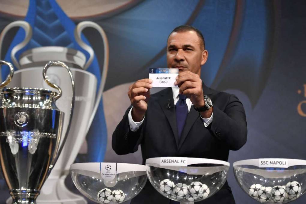 Netherlands' former striker Ruud Gullit shows the name of Arsenal during the draw for the round of 16 of the UEFA Champions League football tournament at the UEFA headquarters in Nyon on December 12, 2016. / AFP PHOTO / Fabrice COFFRINI