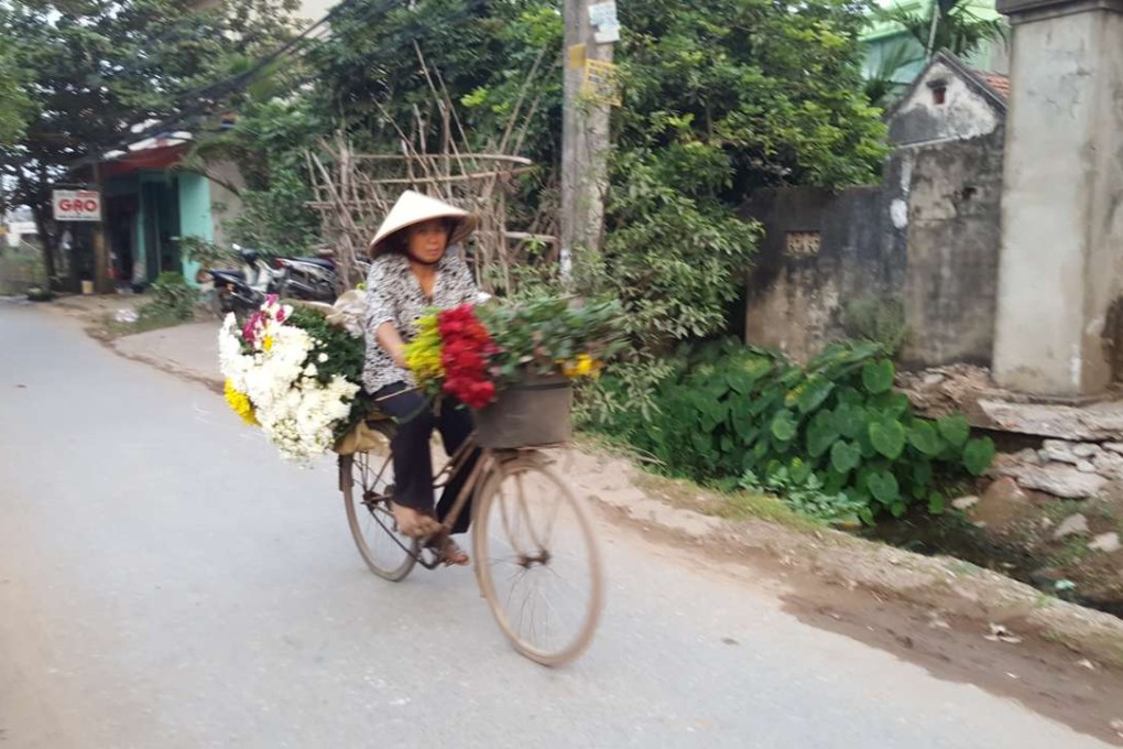 A vendor carries flowers to the market on her bicycle. Photo: Karim Raslan