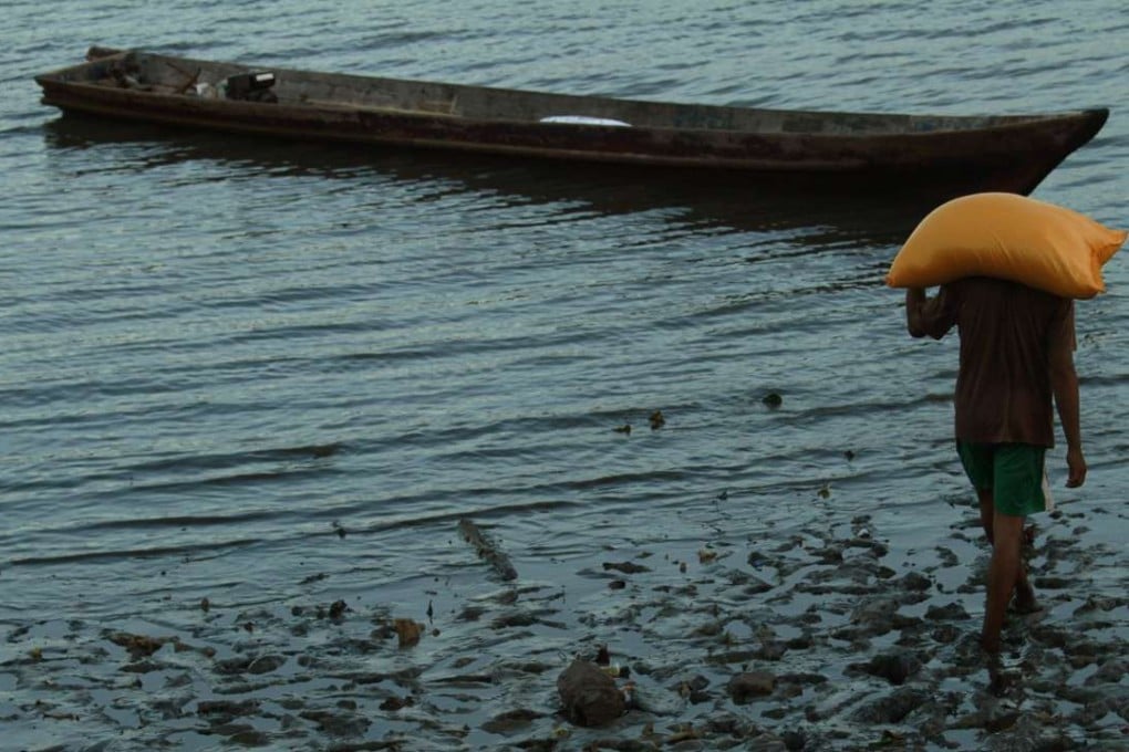 A man carrying a sack of rice walks to board a taxi boat heading for the village of Kendari in Indonesia's southeast Sulawesi province. Most Indonesians are unaware they are paying more for the staple than anywhere in the region. Photo: Reuters