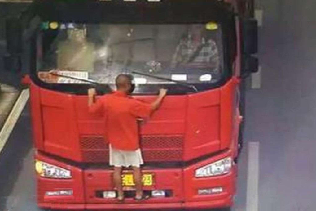 Surveillance footage shows a man clinging to the front of a truck. Drivers are paying people to obscure their licence plates to get around time restrictions designed to ease traffic jams. Photo: Sina