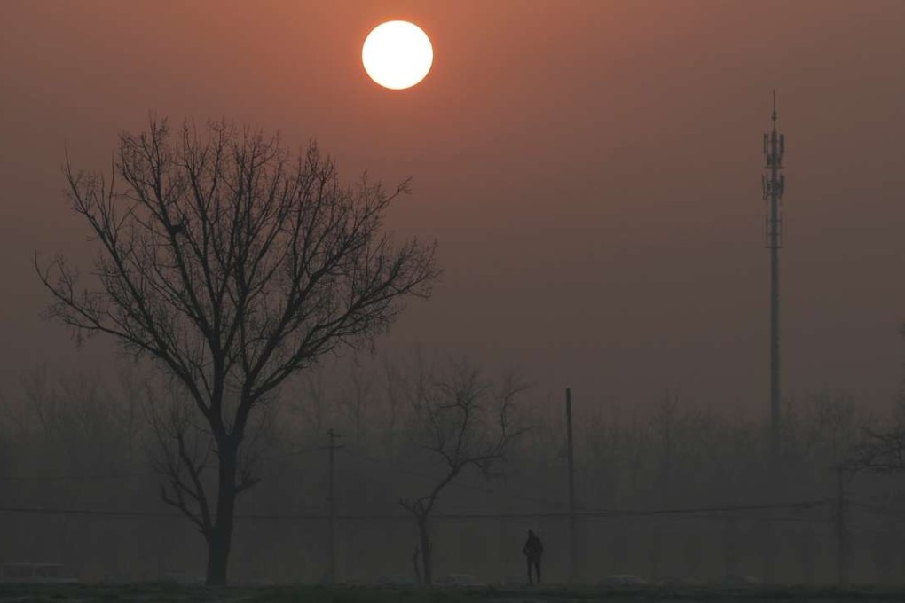 A man walks in the smog as the sun rises over Beijing on Monday. Photo: Reuters