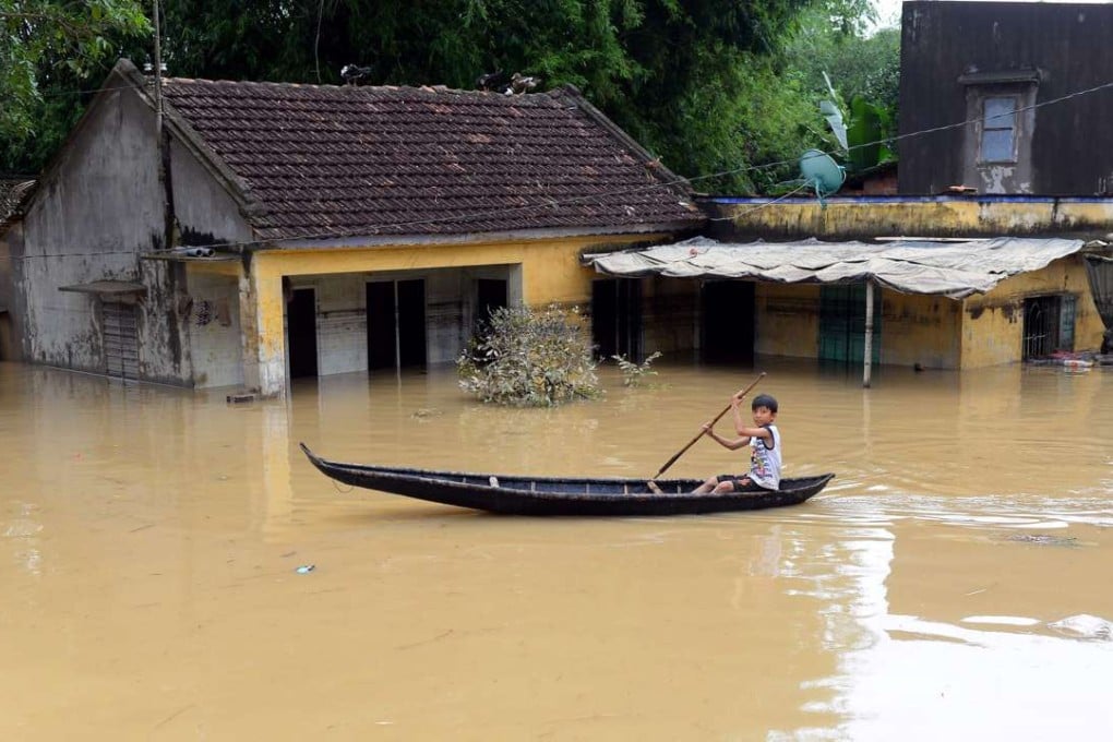 A boy paddling a boat past flooded houses in the central province of Binh Dinh on December 19, 2016. Photo: AFP