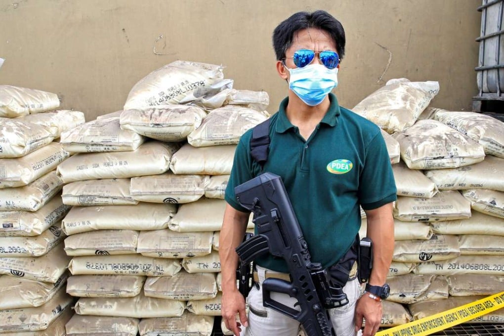 An agent of the Philippine Drug Enforcement Agency armed with an Israeli-made Tavor assault rifle stands guard in front of chemicals used in the production of methamphetamine hydrochloride, or Shabu. Photo: Reuters