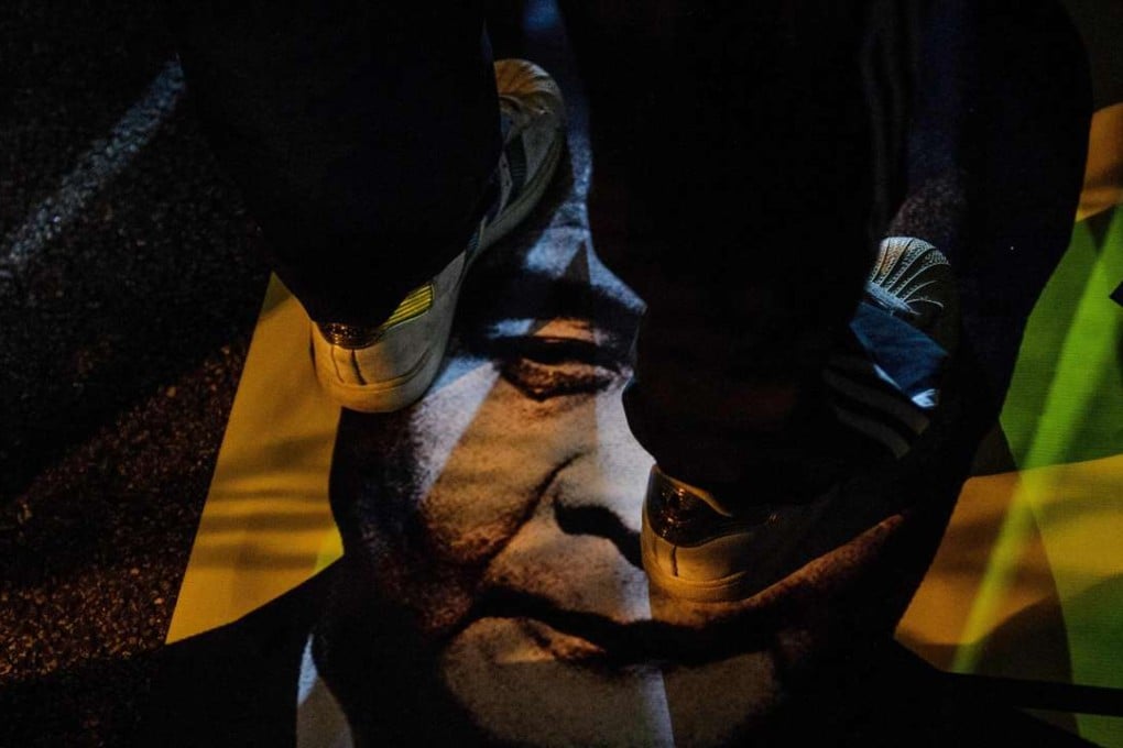 A pro-democracy protester stands on a banner featuring a picture of Chief Executive Leung Chun-ying during a rally. Photo: AFP