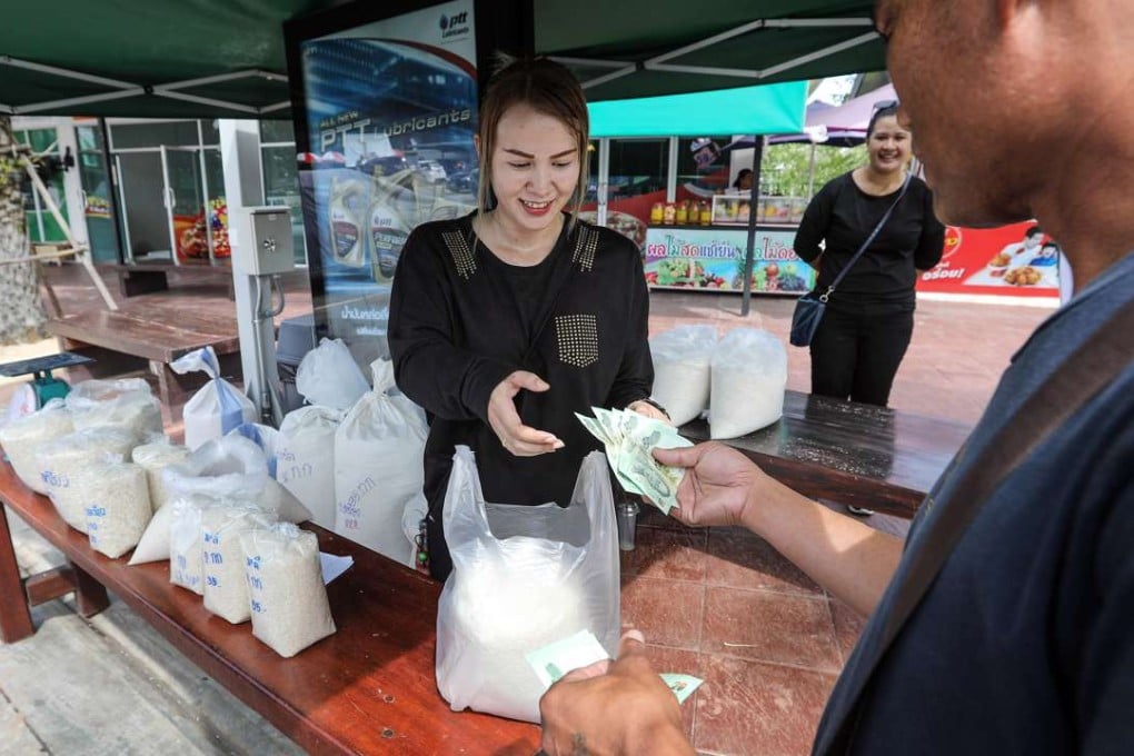 A customer hands over Thai baht banknotes to farmer Suphatson Chanthamon at her rice stall in Ubon Ratchathani. Photo: Bloomberg