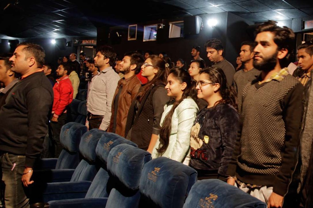 Indian moviegoers stand as the national anthem is played before the screening of a movie at a theatre in Jammu on December 13. India’s Supreme Court has ruled that the anthem must be played before every film screening and audiences must stand. Photo: AP