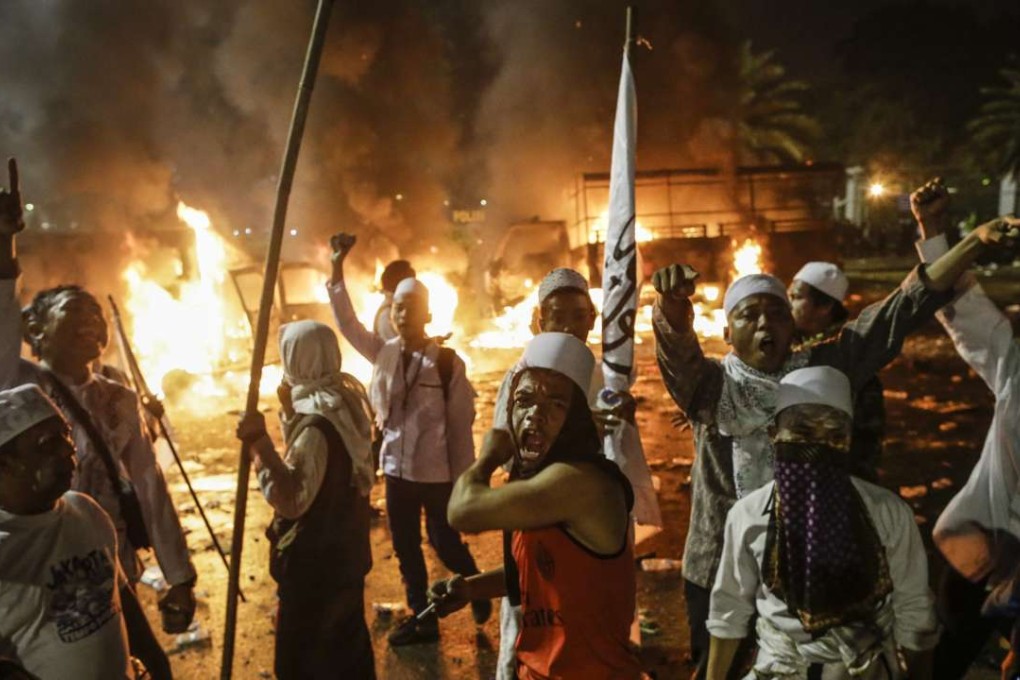 Indonesian protesters near burning police cars during a demonstration against an allegedly blasphemous remark made by Jakarta's Governor Basuki Tjahaja Purnama. Some observers blame online misinformation for Purnama’s predicament. Photo: EPA