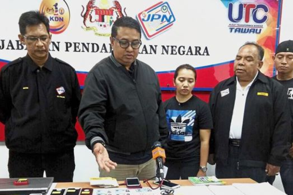 Enormous raid: ﻿Mohamad Yusri (second from left) showing the seized items, including the fake MyKads and cash, at the press conference in Tawau, Sabah. Photo: The Star Online