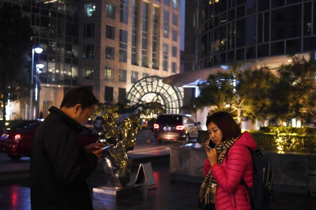 A man and woman use their mobile phones outside a hotel in Beijing. Photo: AFP