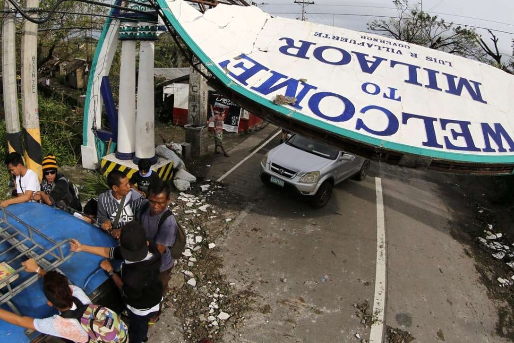 Villagers ride a jeepney next to a toppled signboard in the typhoon-hit city of Naga, Camarines Sur, Philippines. Photo: EPA
