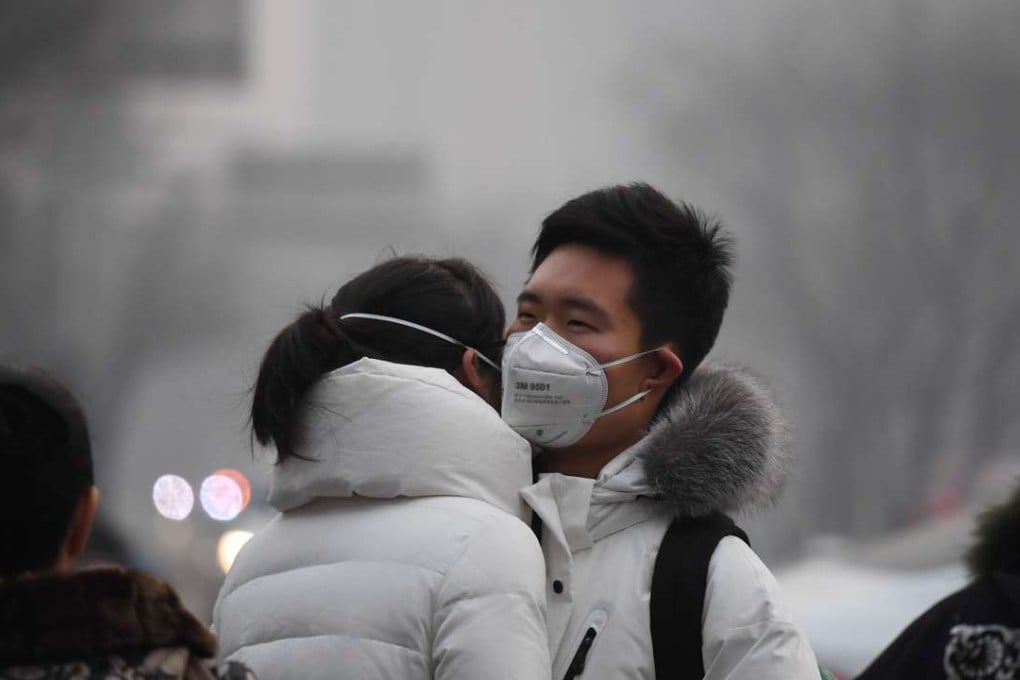 A couple wear masks to help protect themselves from the heavy smog as they embrace on a Beijing street on New Year’s Eve. Photo: AFP
