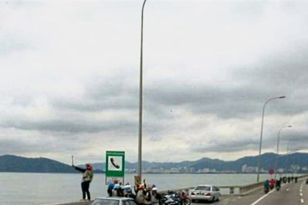 Danger zone: The photo of a motorcyclist taking a selfie while standing on a ledge of Penang Bridge’s rail did not please everyone. Photo: The Star Online