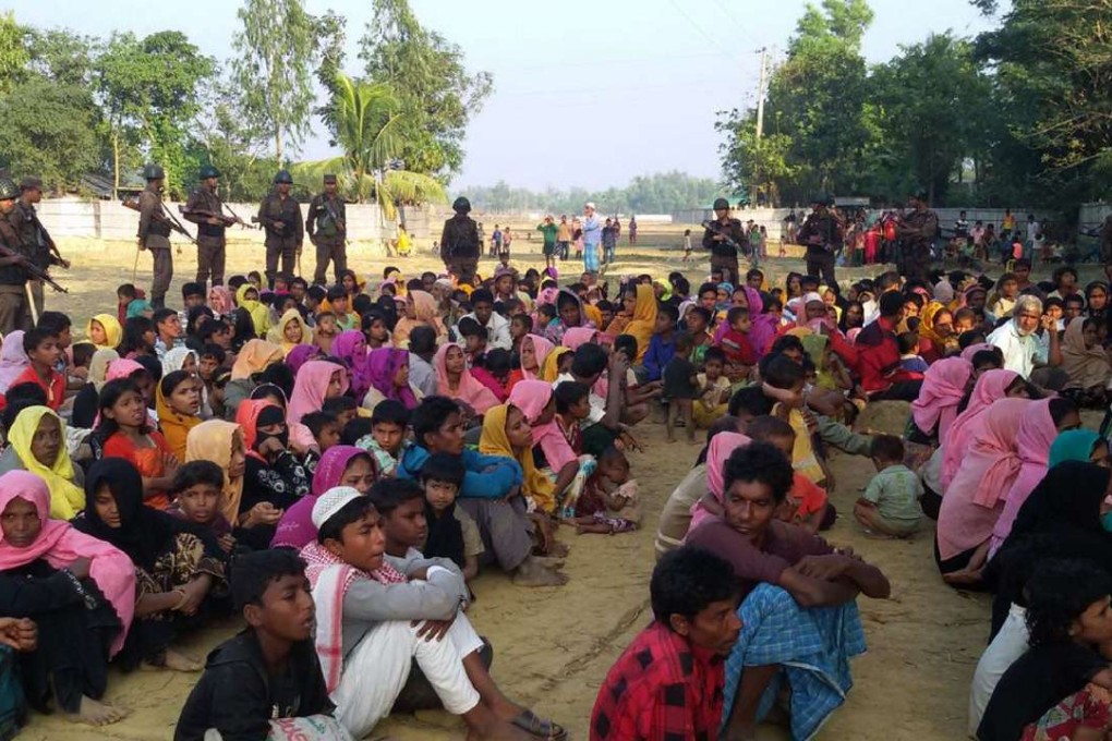 Rohingya Muslims from Myanmar, who tried to cross the Naf River into Bangladesh to escape sectarian violence, are watched by Bangladeshi security officials in Teknaf on December 25. Photo: AFP