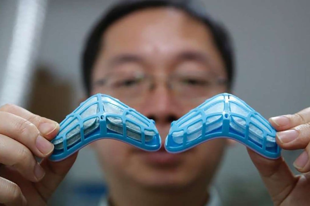 Chinese researcher Liu Yong shows the darkened face mask filter (left), which was exposed to smog for 10 days alongside a new filter. Photo: Chinanews.com
