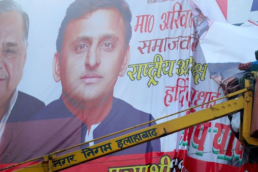 An Indian worker removes a banner poster of Uttar Pradesh chief minister Akhilesh Yadav and his father Mulayam Singh Yadav. Photo: AFP