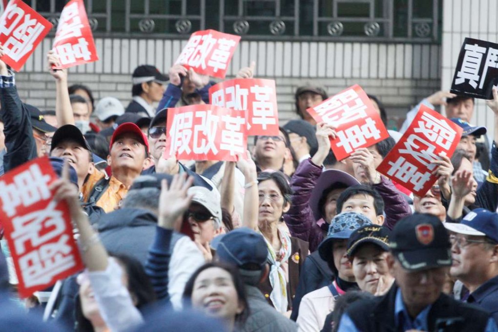 Demonstrators hold placards that reads "False reform" during a protest in Taipei against the reform of Taiwan's deficit-ridden pension scheme on December 31. Photo: Reuters