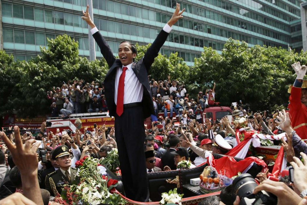 A jubilant President Joko Widodo gestures to the crowd during a street parade following his inauguration in Jakarta on October 20, 2014. After great success with his landmark tax amnesty plan and coalition-building, Widodo may be risking it all by siding with Islamic conservatives. Photo: AP