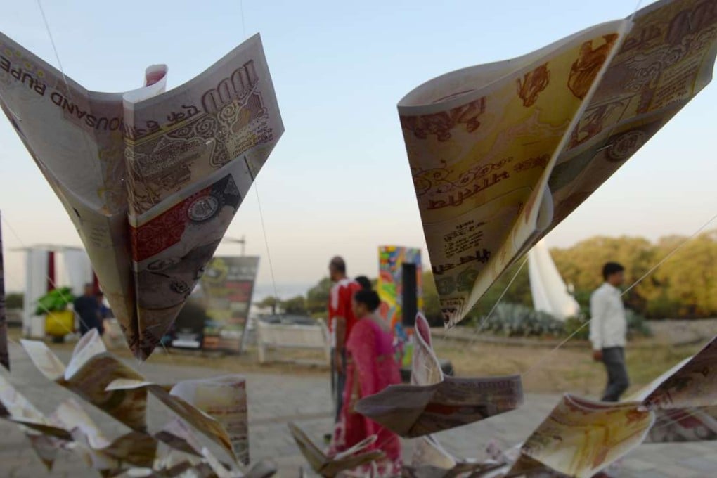 Indians walk past replica prints of the demonetised 500 and 1,000 rupee notes as part of a street art exhibition in Mumbai. Photo: AFP