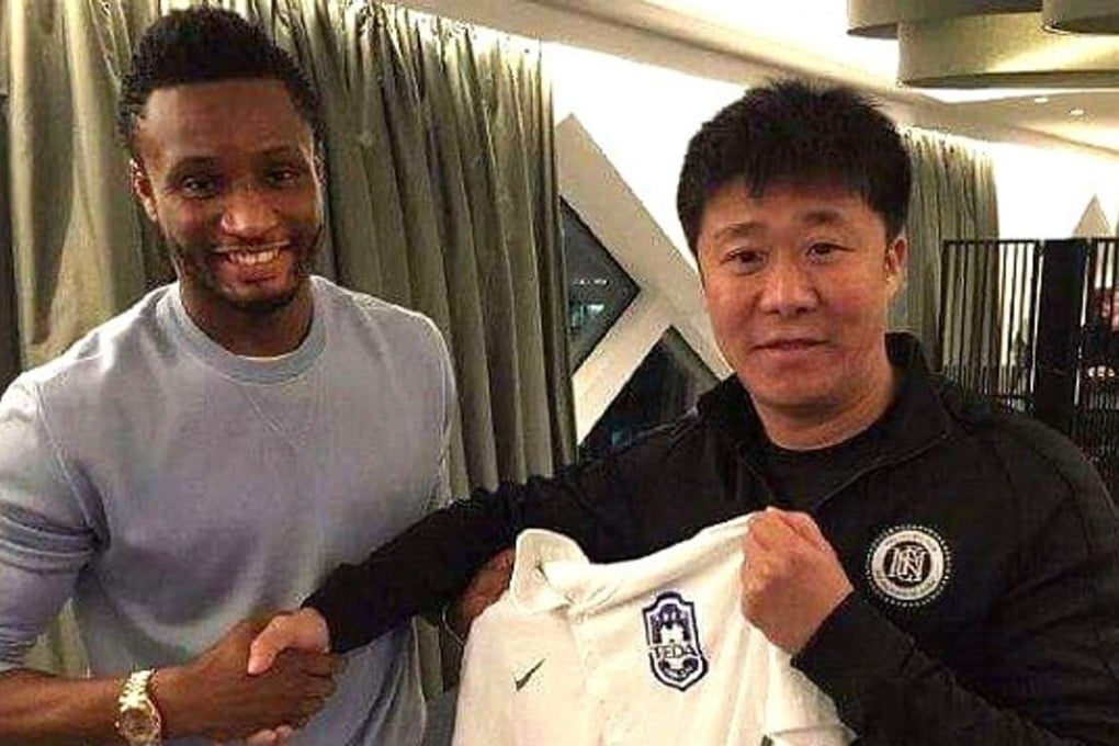 Mikel poses with the Tianjin Teda jersey after putting pen to paper on a three-year deal.