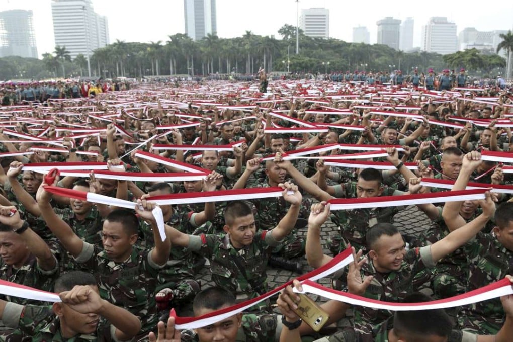 Indonesian soldiers hold up headbands in the colour of the national Red-White flag during a military-sponsored interfaith rally held ahead of a Muslim rally against Jakarta Governor Basuki Tjahaja Purnama. Photo: AP
