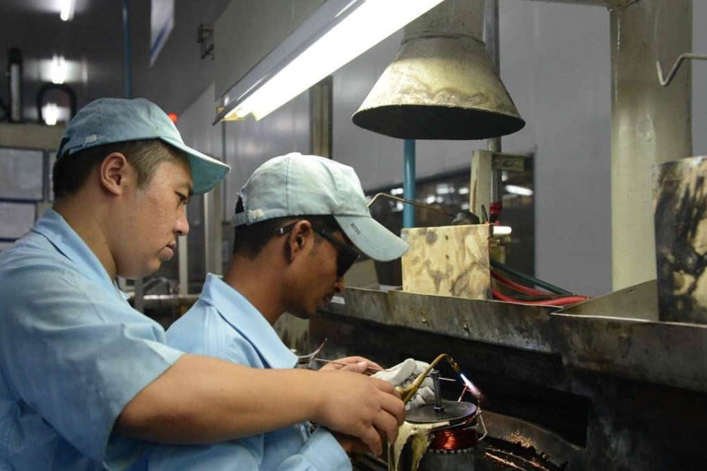 A Chinese supervisor assists an Indian worker as he works on an assembly line of an air-conditioner plant at Matoda, some 20km from Ahmedabad, India. Photo: AFP