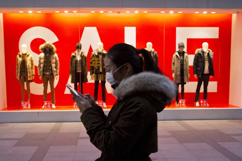 A woman passes mannequins promoting a sale outside a retail outlet in Beijing, China. Photo: AP