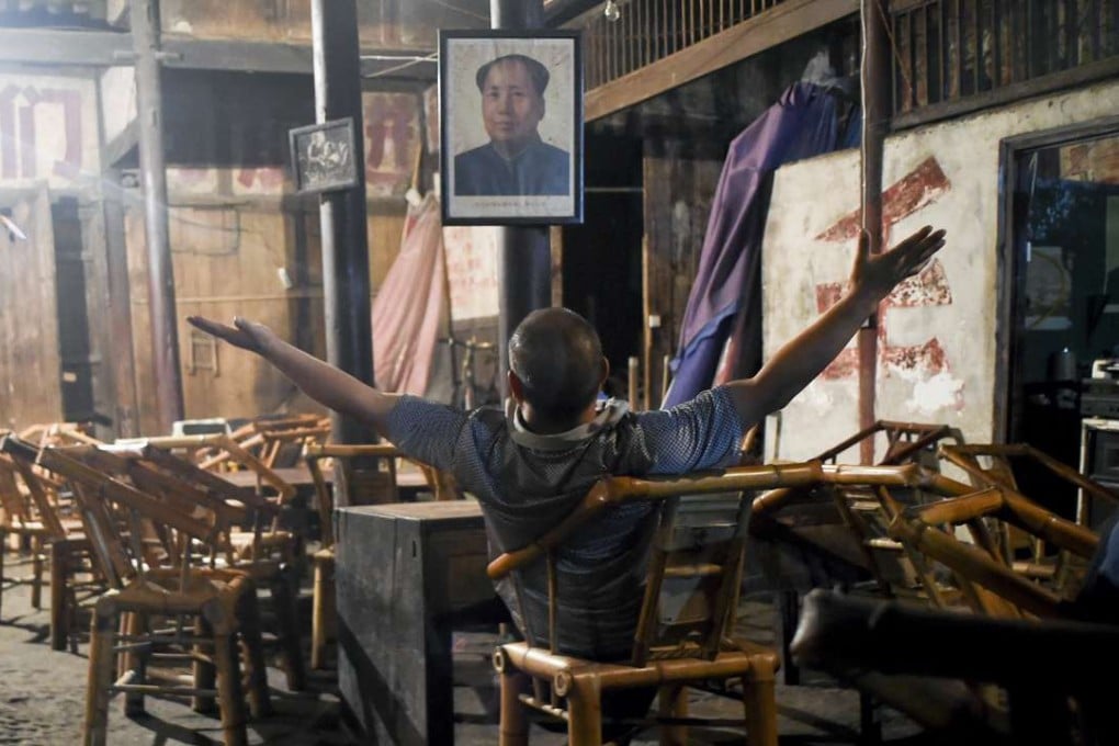 A customer enjoys a stretch under a Mao portrait still in its original position at the Guanyin Pavilion teahouse in Chengdu. Photo: AFP
