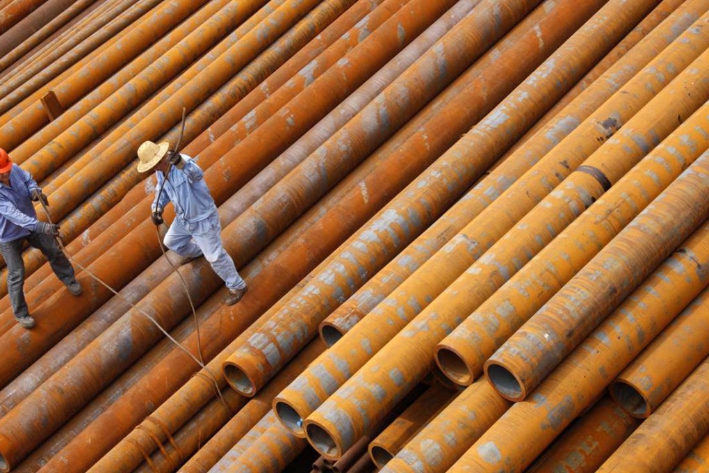 Workers arrange steel pipes at a factory in Huaibei, Anhui province. Photo: AFP