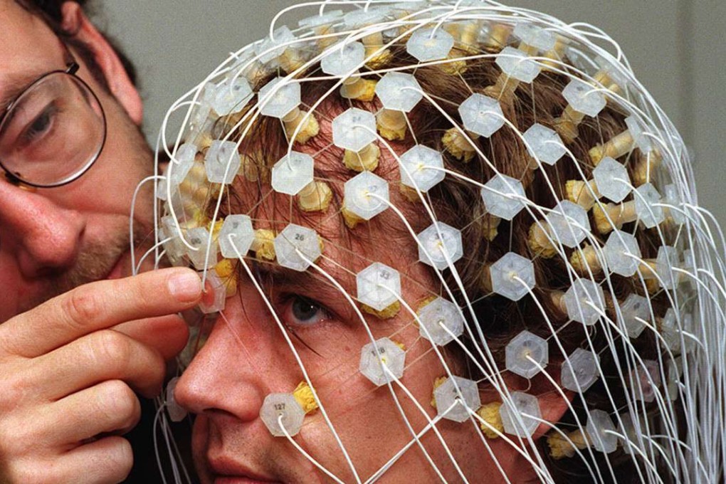 A scientist adjusts a geodesic sensor net on a subject as part of research to capture images of thought processes taking place inside the brain. Phoo: Reuters