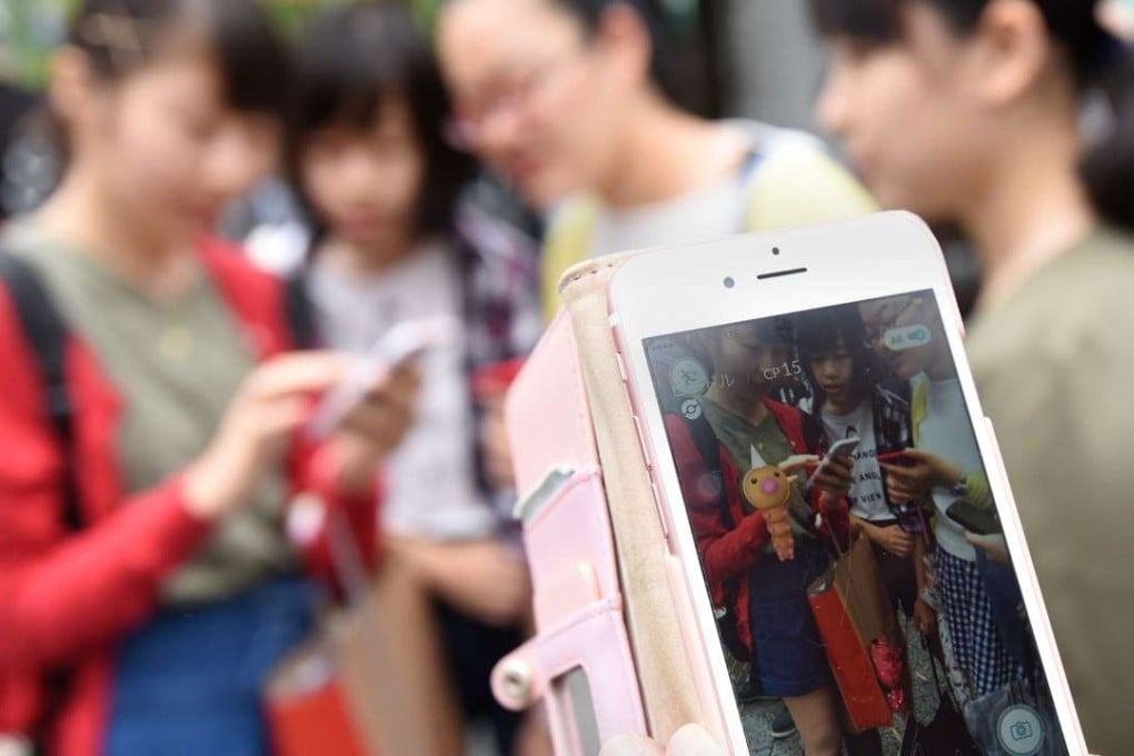 Schoolgirls play Pokemon Go on their mobile phones on a street. Photo: AFP