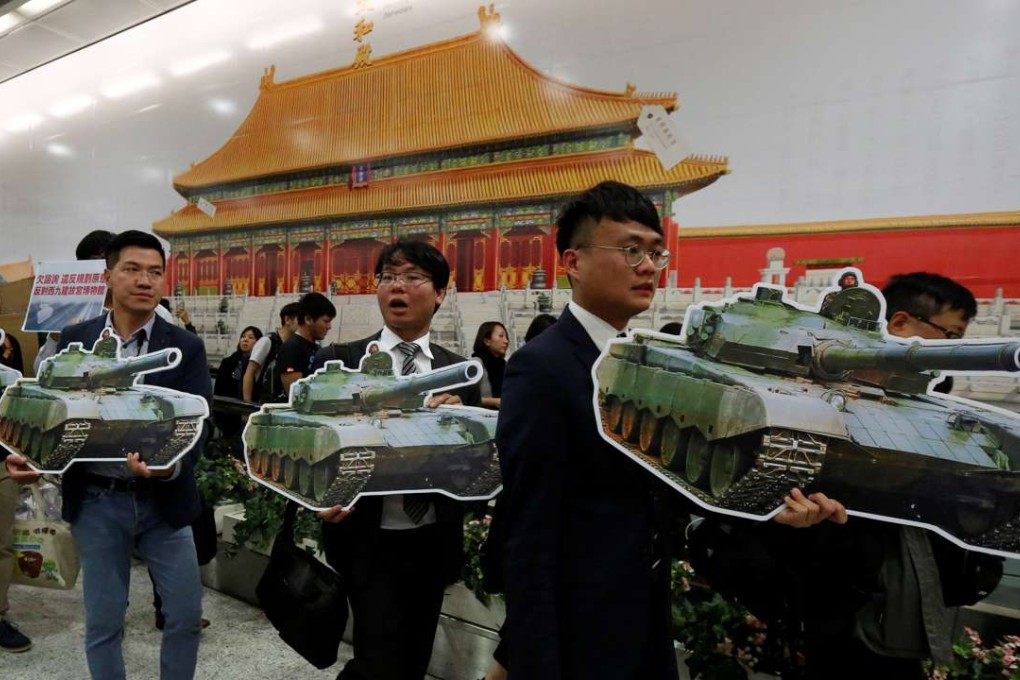 Pro-democracy activists carry cutouts of tanks in front of a poster showing Beijing’s Palace Museum at Central MTR station, during a protest against plans to build Hong Kong’s own version of the museum, on January 10. Photo: Reuters