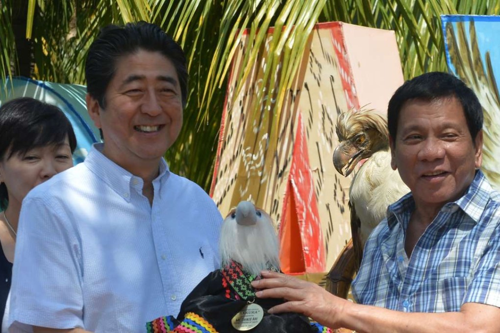 Japanese Prime Minister Shinzo Abe smiles as Philippine President Rodrigo Duterte hands over a gift of a Philippine eagle stuffed toy. Photo: AFP