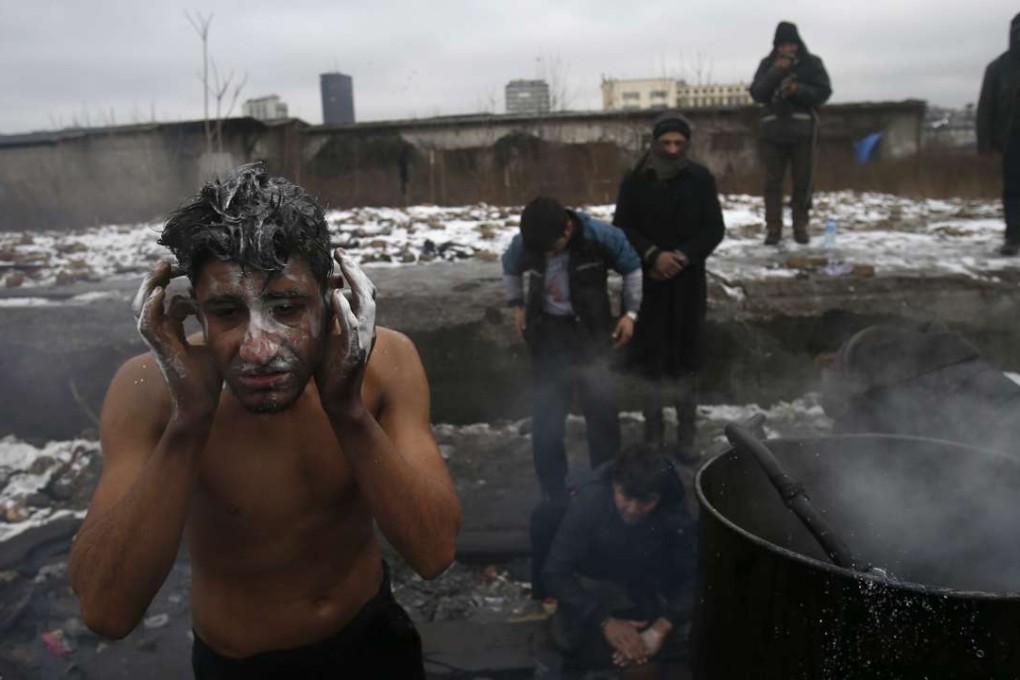 A migrant washes himself outside a crumbling warehouse that has served as a makeshift shelter in Belgrade, Serbia. Photo: AP