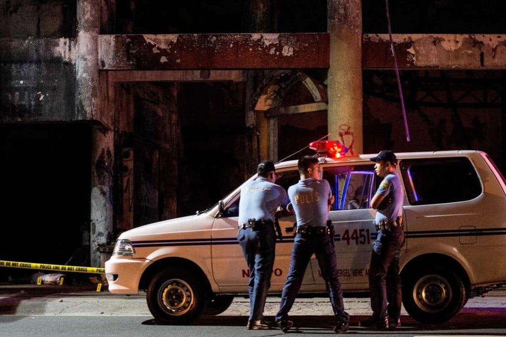 This photo taken on December 23, 2016, shows policemen at the crime scene where the body of an alleged holdaper lies on the street killed by police during an encounter in Manila. People going to mass at one of the most famous churches in the Philippine capital over Christmas were met by a disturbing sight: poster-size pictures of Filipinos dying in pools of blood. The shock Baclaran church exhibit was part of a campaign by one of the nation's oldest and most powerful institutions to stop the killings under President Rodrigo Duterte's war against drugs, which has claimed about 6,000 thousand lives. / AFP PHOTO / NOEL CELIS / TO GO WITH AFP STORY PHILIPPINES-CRIME-RIGHTS-CATHOLIC-CHURCH,FOCUS BY CECIL MORELLA
