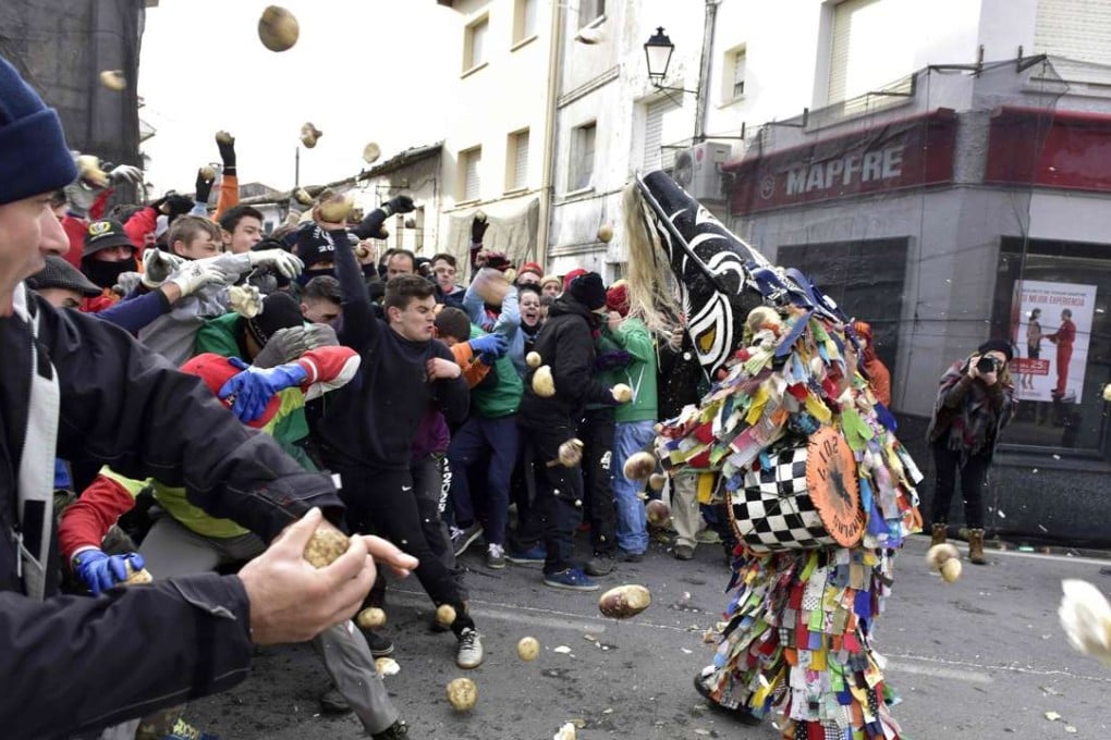People throw turnips at a man representing the Jarrampla, sporting a costume covered in multicoloured ribbons, in Piorna in Spain on Thursday during the annual San Sebastian festivities. Photo: AFP
